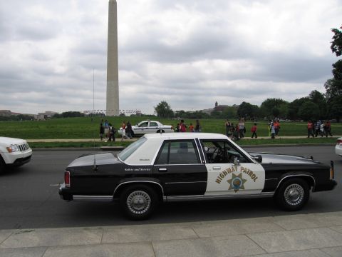 1991 Ford LTD Crown Victoria - Side view of a black-and-white Highway Patrol cruiser with the Washington Monument and parkgoers in the background.