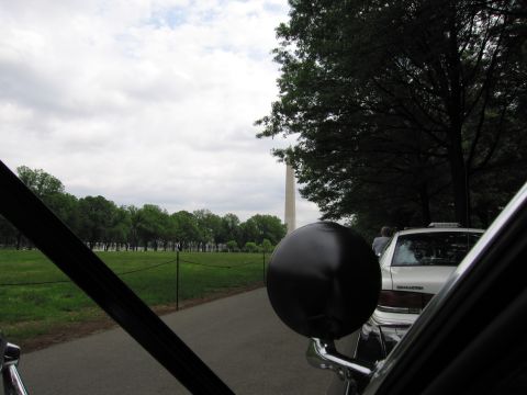 1991 Ford LTD Crown Victoria - Looking out a car windshield toward the Washington Monument, with the vehicle's round side mirror and a white sedan in the foreground.