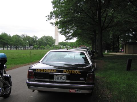 1991 Ford LTD Crown Victoria - black Highway Patrol sedan with gold lettering and a California plate sits beside a motorcycle near the Washington Monument.