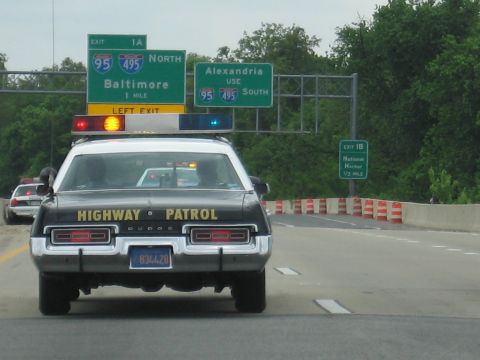 1991 Ford LTD Crown Victoria - rear of a black-and-white Dodge Highway Patrol car drives under green I-95/I-495 signs for Baltimore and Alexandria.