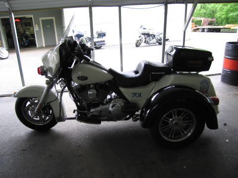 1991 Ford LTD Crown Victoria - white three-wheeled touring motorcycle marked 701 with a black trunk sits in a covered garage bay.