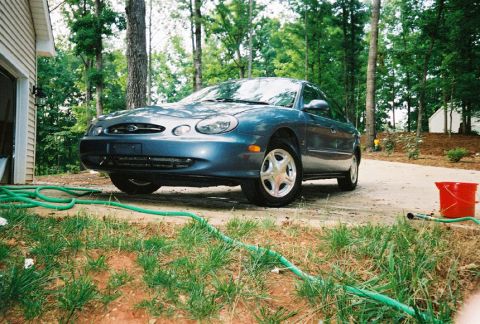 1999 Ford Taurus - A dark blue 1999 Ford Taurus is parked in a residential driveway.