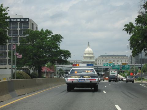 1991 Ford LTD Crown Victoria - Rear view of a Highway Patrol cruiser with lights on driving down a roadway toward the U.S. Capitol dome.
