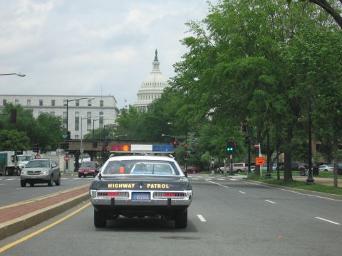 1991 Ford LTD Crown Victoria - black-and-white Highway Patrol cruiser drives down a tree-lined avenue with the U.S. Capitol dome in the distance.