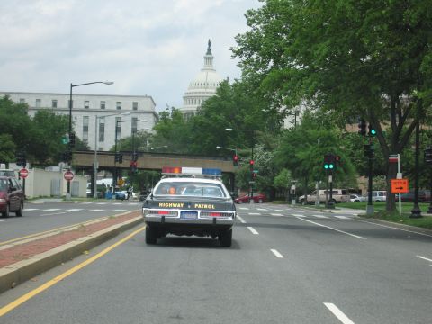 1991 Ford LTD Crown Victoria - Rear view of a Highway Patrol car waiting at a red light on a city avenue with the U.S. Capitol dome behind.