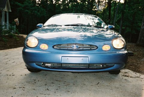1999 Ford Taurus - Front view of a blue sedan, possibly a Jaguar S-Type from around 2000.