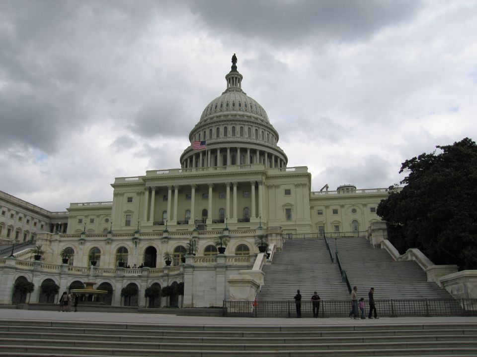 U.S. Capitol building with dome under cloudy sky, viewed from the steps