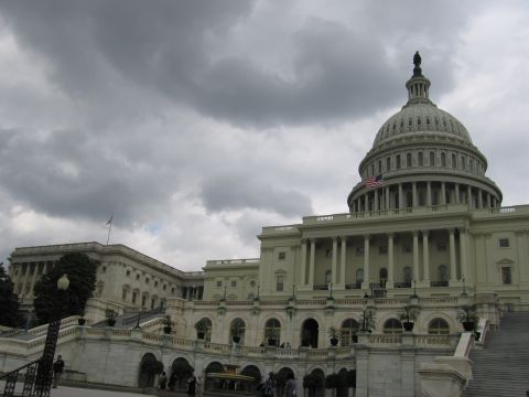 1991 Ford LTD Crown Victoria - white U.S. Capitol with its dome stands beneath heavy gray storm clouds, an American flag flying.