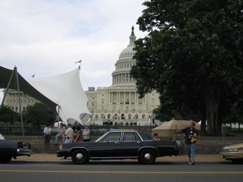 1991 Ford LTD Crown Victoria - black 1980s full-size sedan sits curbside with spectators and a white canopy and the U.S. Capitol behind.