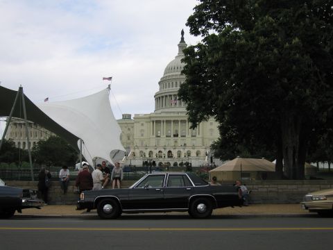1991 Ford LTD Crown Victoria - black 1980s full-size sedan parks along the street as a small crowd gathers near the U.S. Capitol grounds.