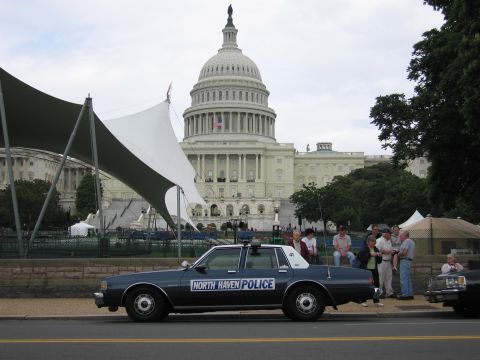 1991 Ford LTD Crown Victoria - boxy dark blue North Haven Police sedan parked near the Capitol while a group of people stand beside it.
