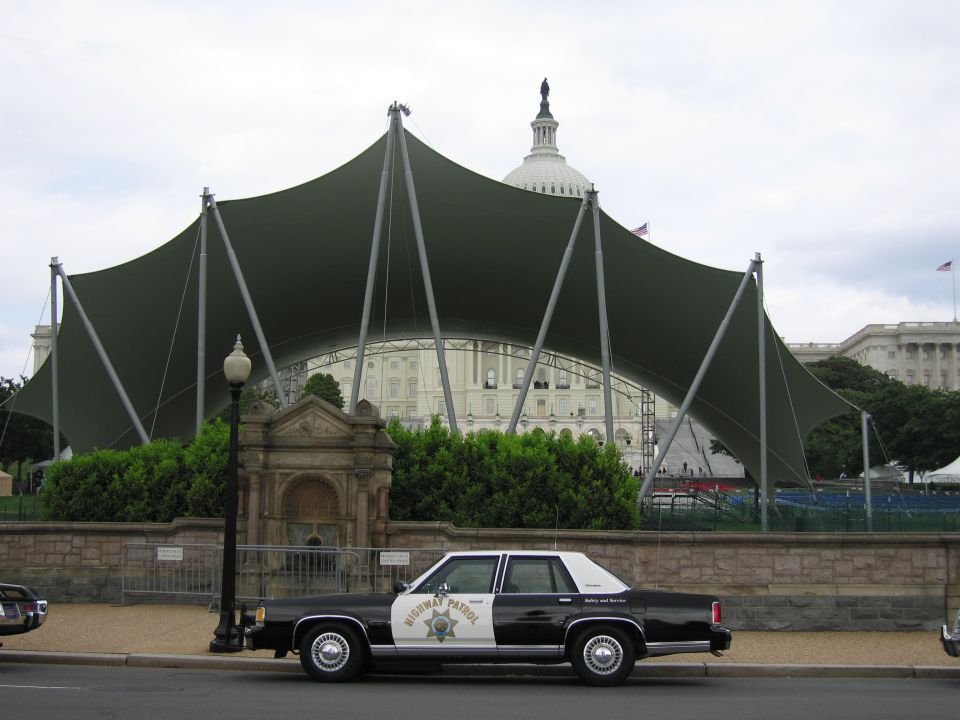 Black and white Highway Patrol sedan before a large green canopy