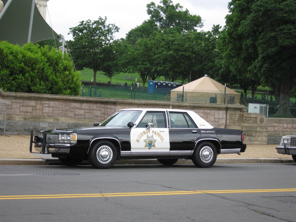 Black and white Highway Patrol sedan with push bar on a roadside