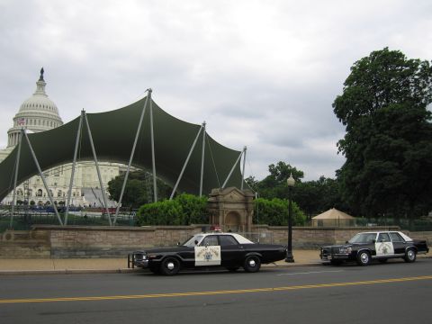 1991 Ford LTD Crown Victoria - Two black-and-white Highway Patrol sedans park curbside before a green canopy with the Capitol dome behind.