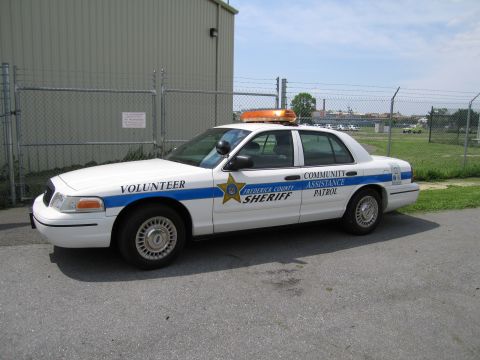 1991 Ford LTD Crown Victoria - white Frederick County Sheriff Volunteer Community Assistance Patrol sedan with amber light bar parked by a chain-link fence.