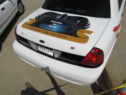 1991 Ford LTD Crown Victoria - Rear view of a white police sedan featuring 'Heroes on Patrol' memorial artwork on the trunk lid in a parking lot.