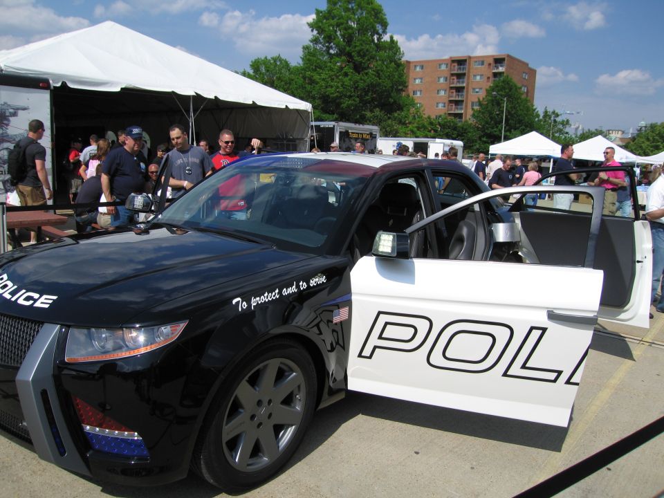 Black-and-white concept police car with doors open at an outdoor display
