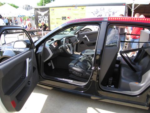 1991 Ford LTD Crown Victoria - View through the open doors of a black police vehicle showing its dark interior seats and pillars at an outdoor display.