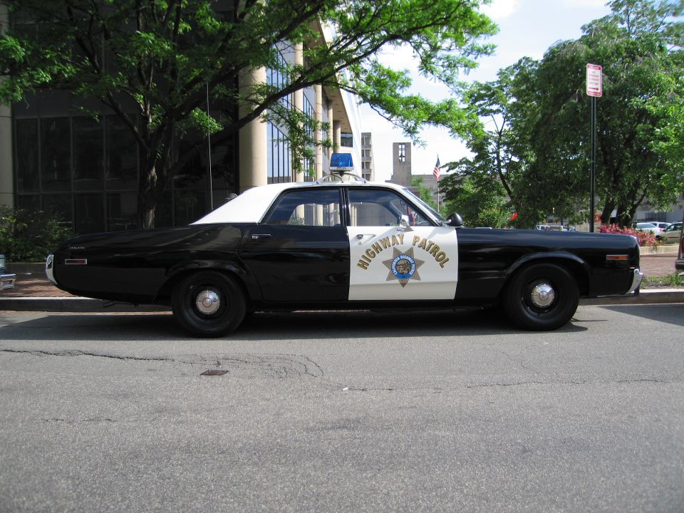 Side view of a black and white Highway Patrol sedan parked on a street