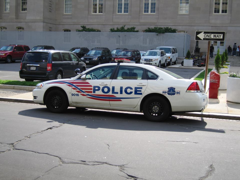 White Metropolitan Police sedan with red and blue stripe parked by a one-way sign