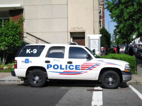 1991 Ford LTD Crown Victoria - white Police K-9 SUV lettered POLICE with red-and-blue striping is parked in front of a Lutheran church.