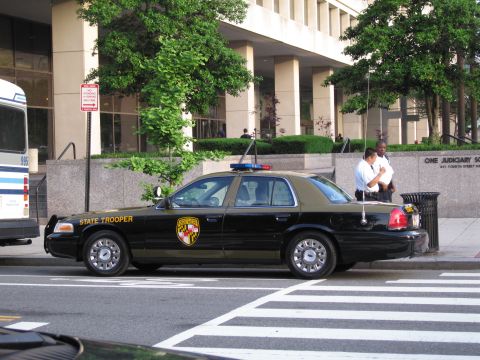 1991 Ford LTD Crown Victoria - black and tan Maryland State Trooper police sedan parked at a crosswalk in front of a courthouse building.