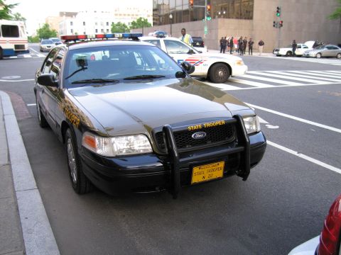 1991 Ford LTD Crown Victoria - Front three-quarter view of a black and tan Maryland State Trooper Ford with a push bumper at a crosswalk.
