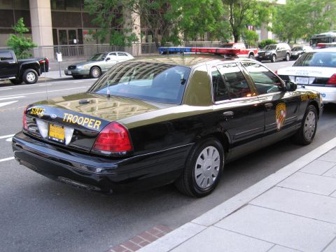 1991 Ford LTD Crown Victoria - Rear three-quarter view of a black and tan Maryland State Trooper sedan parked among other police cars on a street.