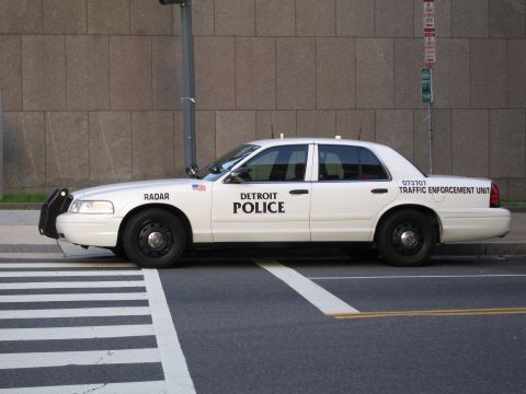 1991 Ford LTD Crown Victoria - white Detroit Police Ford traffic enforcement sedan marked RADAR parked beside a stone wall and crosswalk.