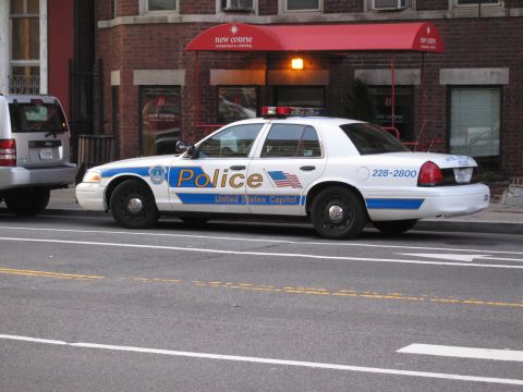1991 Ford LTD Crown Victoria - white United States Capitol Police Ford sedan parked curbside in front of a brick building with a red awning.