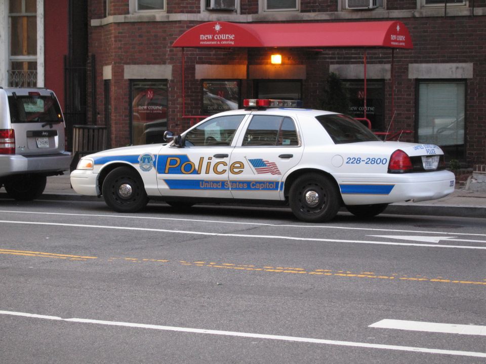 White US Capitol Police Ford sedan parked by a restaurant awning