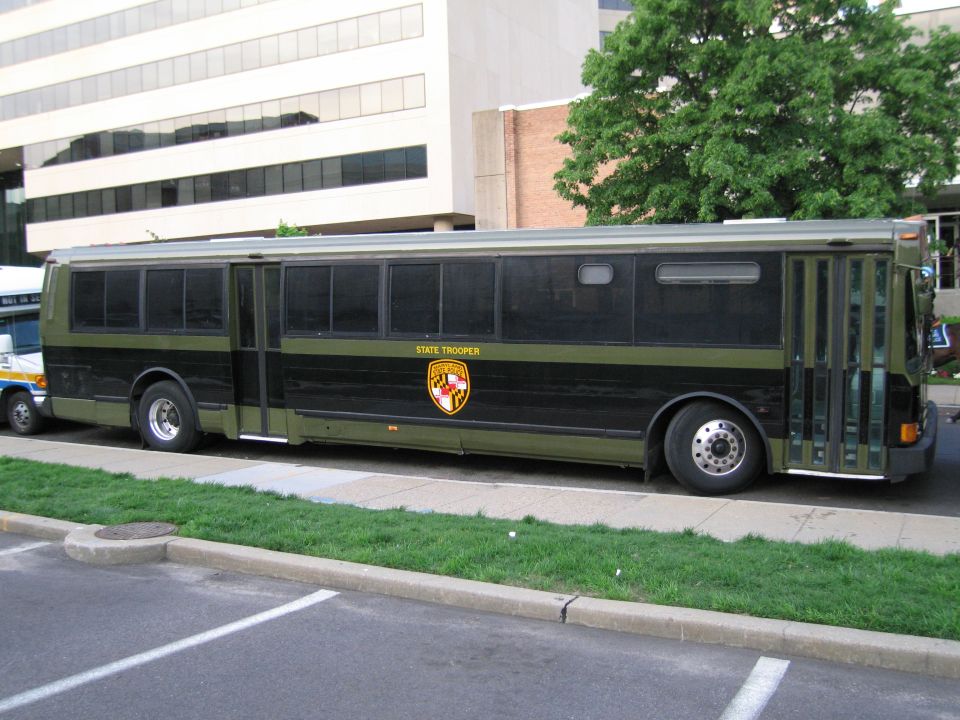 Olive and black Maryland State Trooper bus parked in a lot