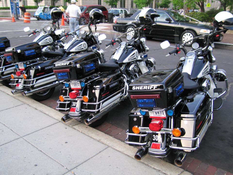 Rear view of three black Harley-Davidson Sheriff police motorcycles parked at a curb