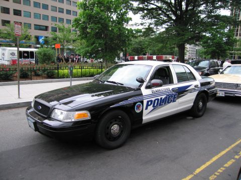 1991 Ford LTD Crown Victoria - black-and-white Ford Crown Victoria patrol car bearing CLARKSTOWN POLICE markings parked at a tree-lined city curb.