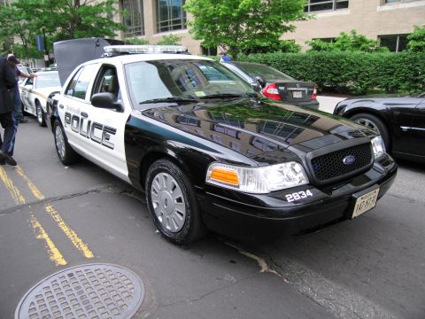 1991 Ford LTD Crown Victoria - black-and-white Ford Crown Victoria patrol car marked POLICE and numbered 2834 with a roof light bar parked on a city street.