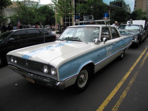 1991 Ford LTD Crown Victoria - two-tone blue-and-white vintage Dodge four-door police sedan lettered Detroit Police with twin spotlights parked on a city street.
