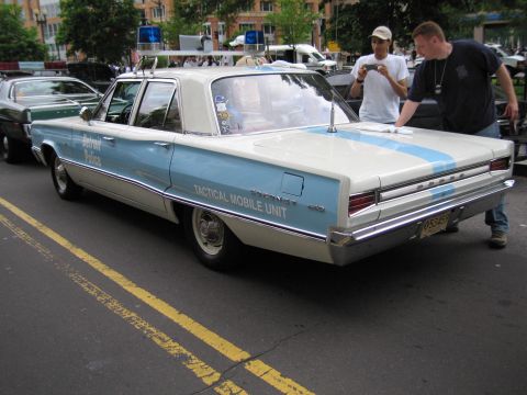 1991 Ford LTD Crown Victoria - Rear view of a blue-and-white vintage Dodge sedan lettered Detroit Police TACTICAL MOBILE UNIT as people photograph it on a city street.