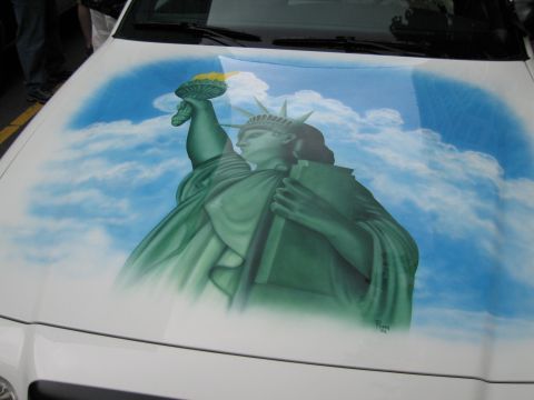 1991 Ford LTD Crown Victoria - white vehicle's hood is custom airbrushed with the Statue of Liberty against a blue cloud-filled sky.