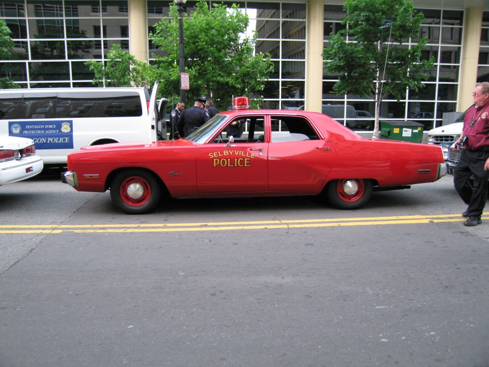 Red Selbyville Police sedan, driver-side profile on street