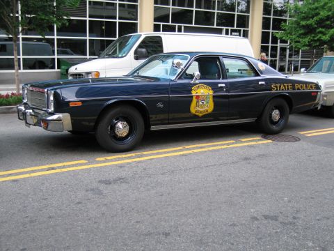 1991 Ford LTD Crown Victoria - dark navy State Police sedan with gold lettering and a department shield decal, parked along a yellow-striped street.