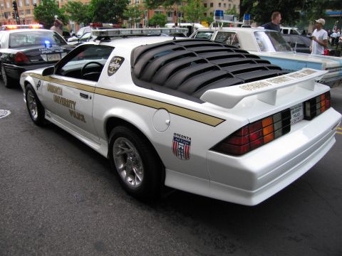 1991 Ford LTD Crown Victoria - white University Police sport coupe with gold striping and louvered rear window, viewed from the rear quarter at a car event.
