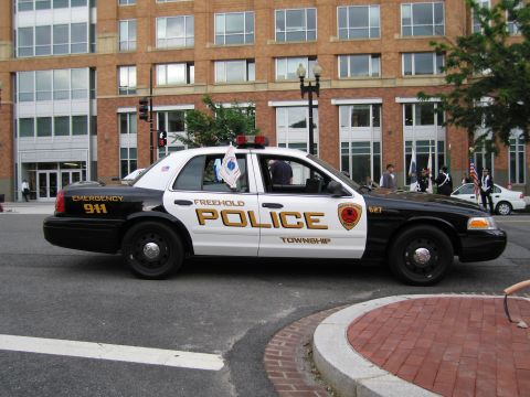 1991 Ford LTD Crown Victoria - black-and-white Freehold Township Police Ford Crown Victoria with gold lettering rounds a brick-edged street corner.