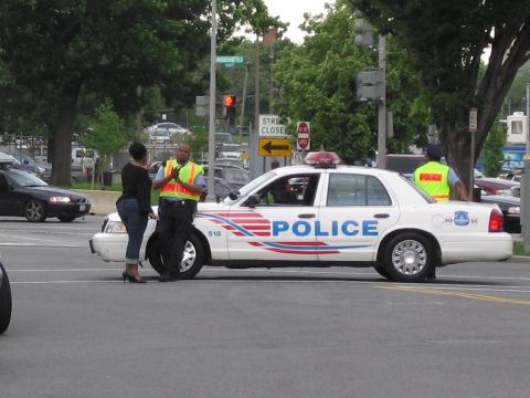 1991 Ford LTD Crown Victoria - white Metropolitan Police cruiser marked 516 sits at an intersection as officers in yellow safety vests work nearby.
