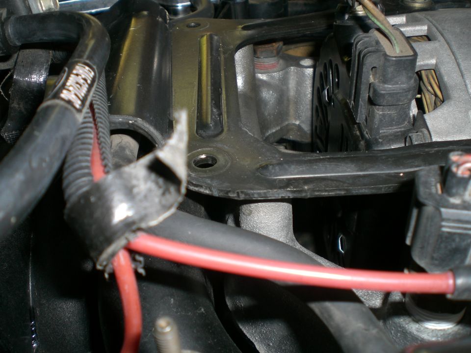 Engine bay close-up: red wire in broken black clip near bracket and alternator