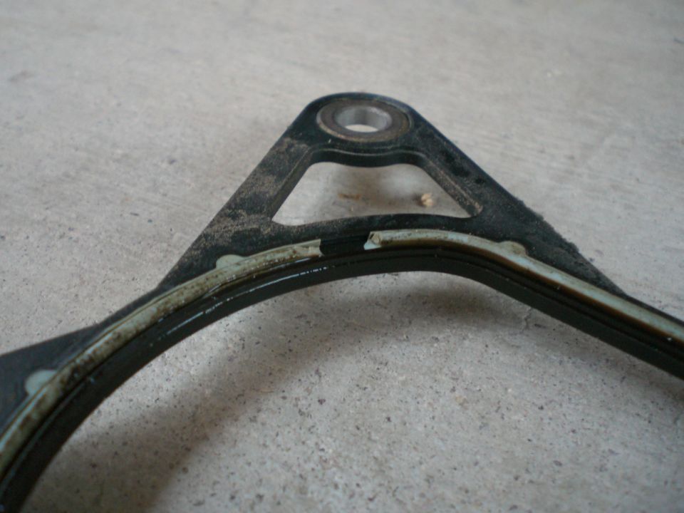 Damaged engine gasket with torn sealing material on a concrete surface