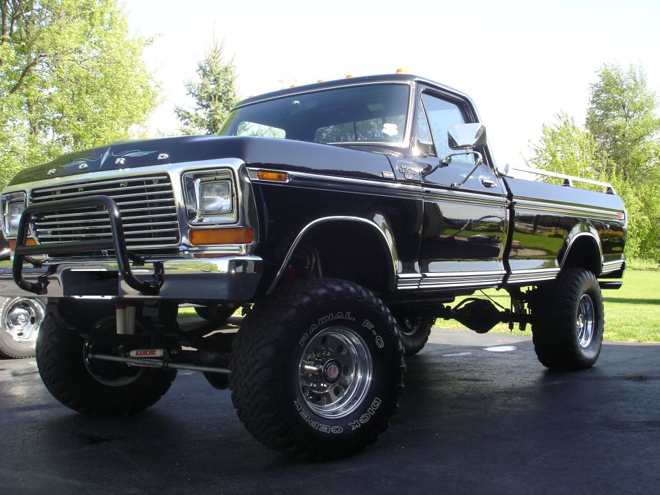 Lifted black 1970s Ford 4x4 pickup on Dick Cepek mud tires, front three-quarter view