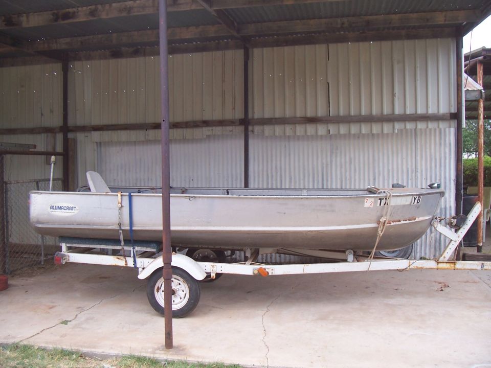 Aluminum boat on a trailer under a corrugated metal roof