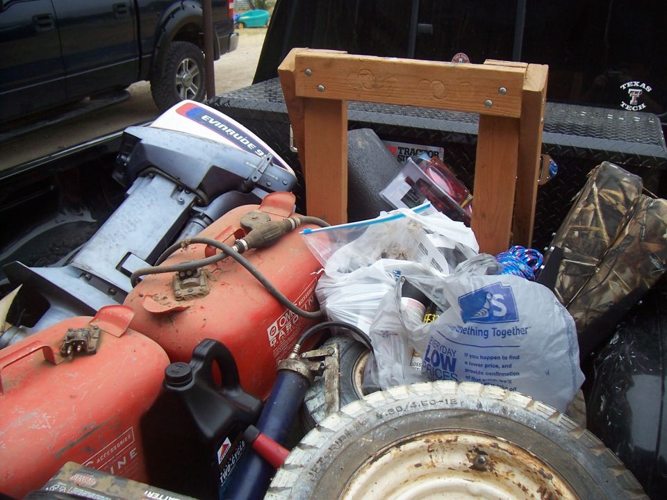 Boat motor, red fuel cans, and a spare tire in a truck bed