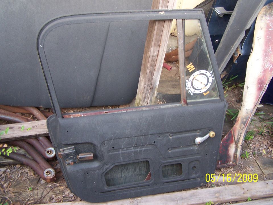Black car door with a silver handle and a circular sticker on the window