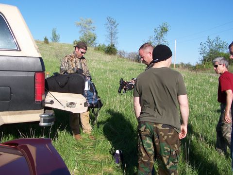 1986 Ford Bronco - A group of men gather around the back of a tan and black SUV, which is loaded with bags and equipment.